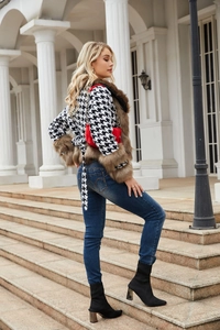 Detailed close-up of houndstooth jacket with brown faux fur collar and red chain bag