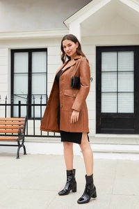Detail of a brown faux leather trench coat featuring large lapels and oversized side pockets
