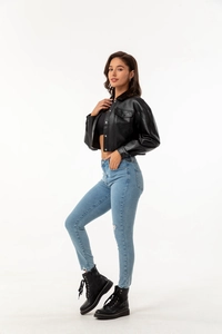 Side view of a black faux leather jacket paired with ripped denim jeans and chunky boots