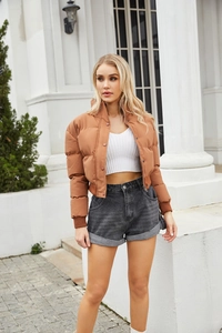 Detail of caramel puffer jacket with high collar and snap buttons in outdoor setting