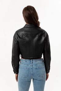 Rear view of a black faux leather jacket paired with light blue washed denim jeans