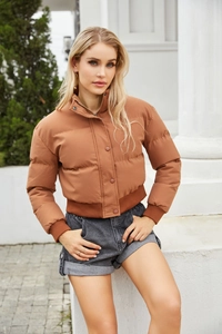 Detail of caramel brown puffer jacket showing stand collar and ribbed hem textures