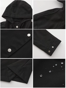 Detail view of water-resistant black hooded jacket with silver snap buttons and adjustable cuffs