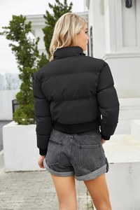 Detail of black puffer jacket showing ribbed hem, cuffs and horizontal quilting