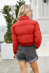 Close-up of women's bright red cropped puffer jacket with stand collar and quilted texture
