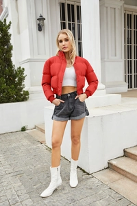 Outdoor street style view of a red short puffer jacket with high collar and snap buttons