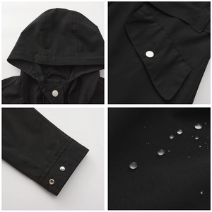 Macro detail of waterproof black hooded jacket showing water beads and silver metal snaps