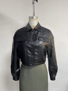 Detail showing the classic black faux leather texture and symmetric chest pockets of the jacket