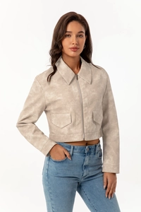 Close-up of cream faux suede jacket featuring sharp collar and metal zipper detail