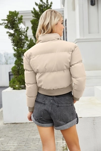 Rear view of beige short puffer jacket with high collar and ribbed cuffs for women