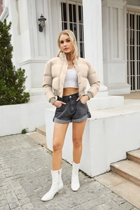 Close-up of cream puffer jacket featuring a high collar with zipper and button closure