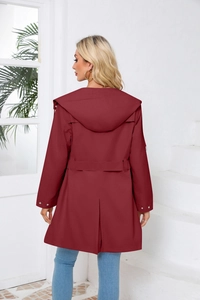 Detail view of the back of a burgundy hooded trench coat with rain shield and waist belt