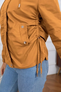 Detail of ginger yellow hooded jacket showing snap buttons and side drawstring design