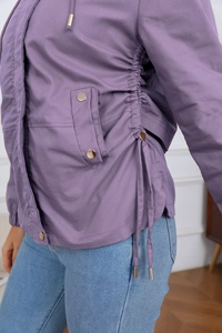 Detail view of purple hooded windbreaker featuring gold metal buttons and waist drawstrings
