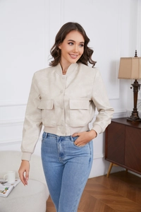 Detail of loose beige bomber jacket featuring flap pockets and ribbed cuffs