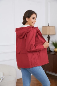 Detail of red hooded windbreaker featuring adjustable drawstring waist and large flap pockets