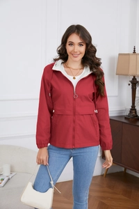 Detail of red hooded windbreaker featuring a silver ring zipper and white hood lining