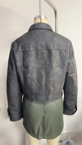 Detail view of the back of a dark gray PU leather biker jacket with stitching and buckle details