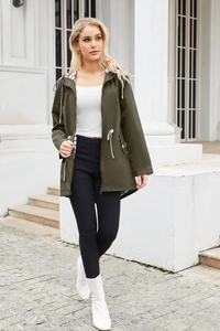 Outdoor street view of a hooded dark olive windbreaker with drawstrings and zipper