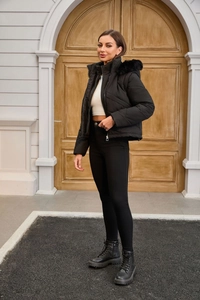 Close-up of black quilted puffer jacket with oversized faux fur hood and sleek metal zipper