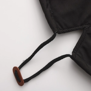 Detailansicht der schwarzen Jacke mit Kordelzug und braunem Leder-Kordelstopper am Bund