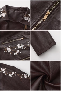Détails de broderie florale blanche et fermetures éclair dorées sur veste en cuir marron