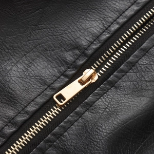 Close-up of golden metal zipper and black pebble-grained leather jacket detail