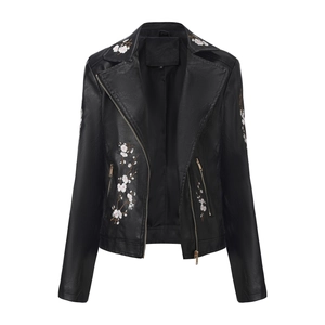 Détail de broderies florales blanches sur une veste de motard en similicuir noir à zip