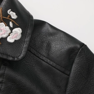 Close-up of intricate floral embroidery on the collar of a black leather jacket