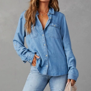 Close-up of light blue denim shirt showing dual flap pockets and classic button closure