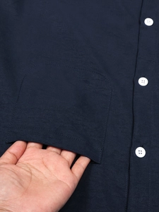 Detail of navy linen shirt showing the large front pocket and white button contrast