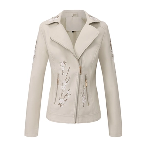 Détails de broderie florale sur le revers et la manche d'un blouson en similicuir beige