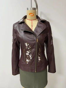Close-up of floral embroidery on a burgundy leather biker jacket with gold zipper details