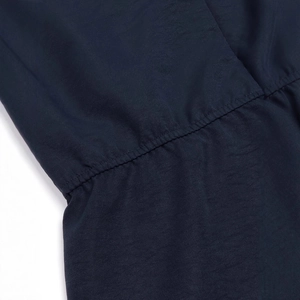 Detail view of navy blue jumpsuit showing waist gathering and pleated stitching texture