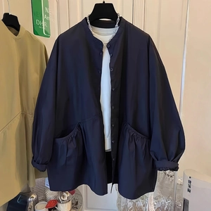 Detail view of navy blue high-neck jacket featuring large pleated pockets and button closure
