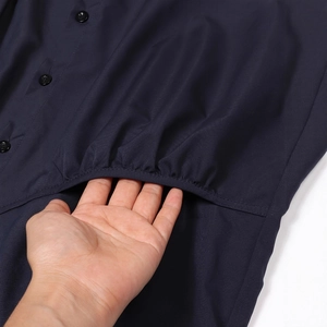 Detailed view of elastic gathered hem and black resin button on navy blue jacket
