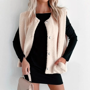 Détail du gilet beige en polaire à boutons argentés sur une robe noire côtelée à manches