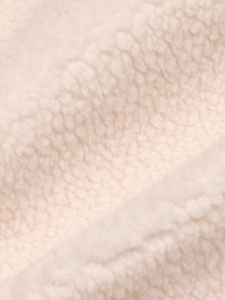 Vue macro détaillée de la texture du tissu en peau de mouton crème aux fibres bouclées