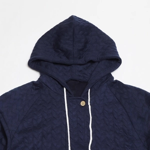 Detail of blue quilted hooded jacket featuring textured fabric and white drawstring