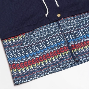 Detail of hooded jacket featuring quilted navy fabric and ethnic geometric print patterns