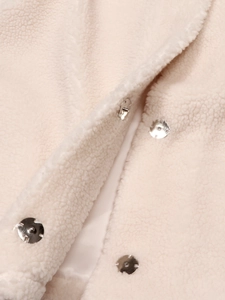 Gros plan du gilet en laine beige avec boutons-pression argentés et texture chaude