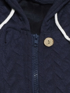 Detail view of navy quilted hooded jacket featuring a wooden button and blue zipper