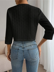Minimalist black textured crewneck jacket paired with slim blue denim jeans