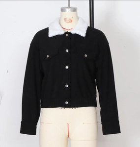 Detail of black corduroy jacket fabric texture with white faux fur collar and pockets