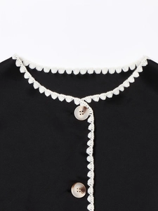 Detail of white crochet lace trim and marble buttons on a black autumn jacket