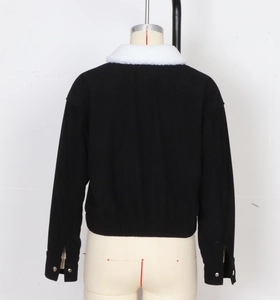 Detail view of black corduroy jacket back with white faux fur collar and metal button cuffs