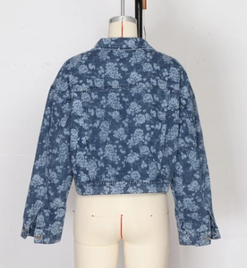 Close-up back view of a blue denim jacket featuring vintage floral patterns and metal buttons