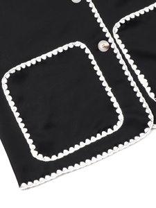 Close-up of black cardigan with white crochet lace edges and square pocket detail