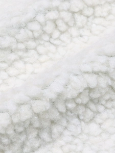 Gros plan sur un tissu polaire sherpa blanc avec texture bouclée douce et fibres épaisses