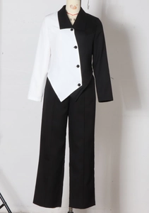 Detail of asymmetric black and white patchwork blazer with buttons and wide leg trousers